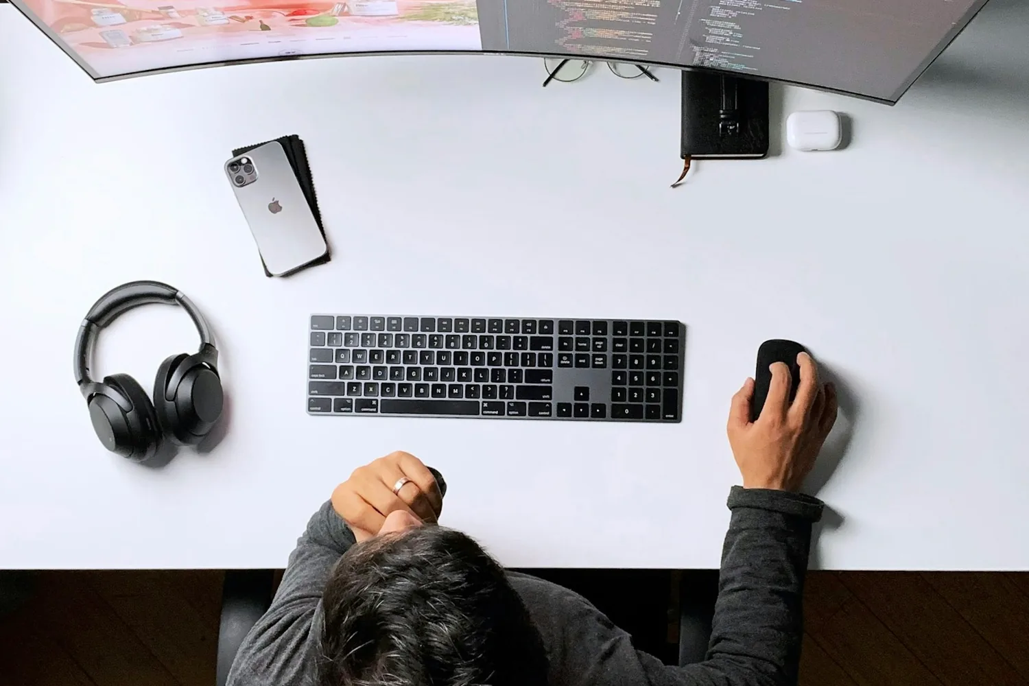 Vue de dessus d’un poste de travail : un casque audio, un clavier et un téléphone posés sur un plan blanc
