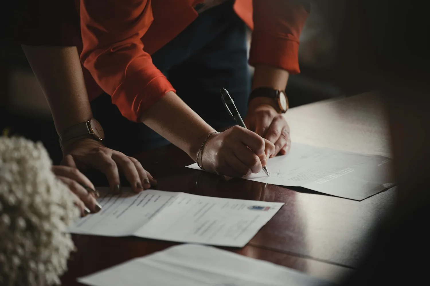 Deux personnes signant un document autour d’une table de travail