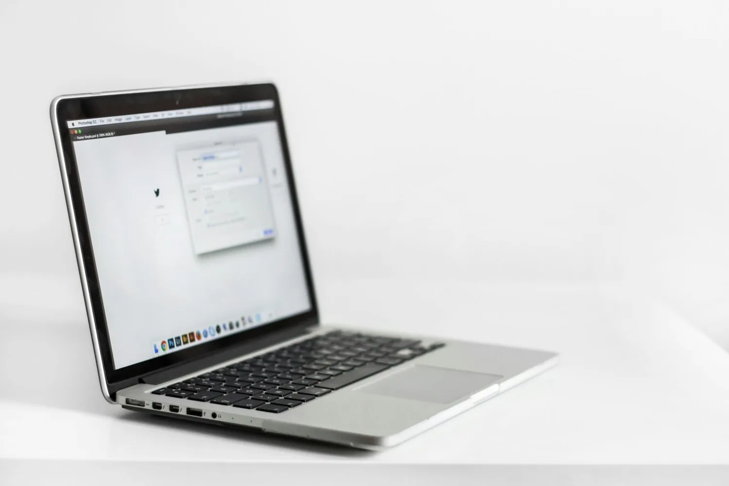 Ordinateur portable ouvert sur une table blanche, dans un décor clair
