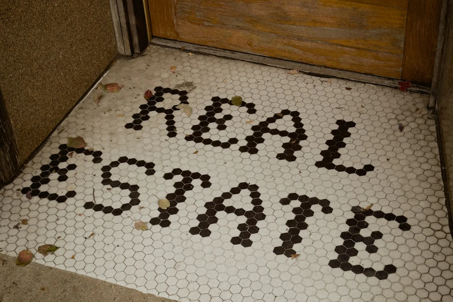 Petits carreaux hexagonaux formant les mots « real estate » sur le seuil d’une porte en bois
