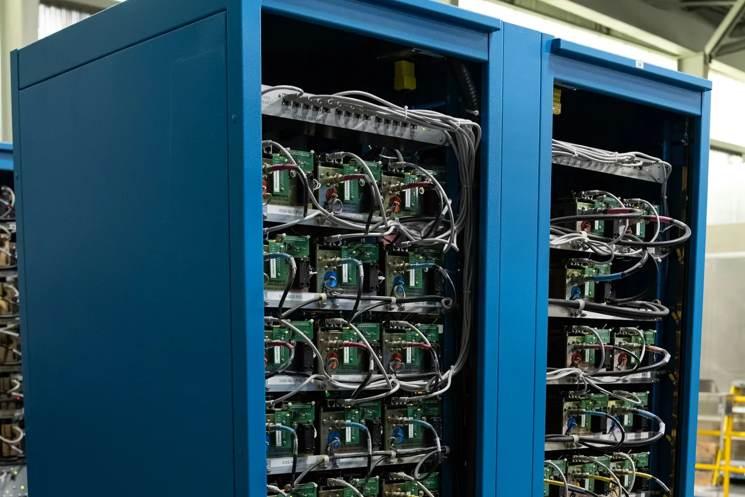 Baies de serveurs ouvertes dans une salle machine, leurs montants peints en bleu