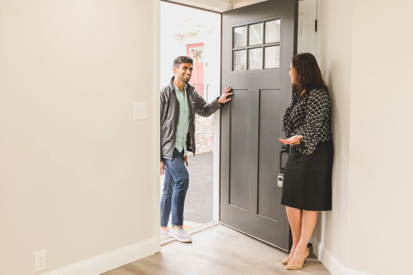 Agent immobilier accueillant des clients à la porte d’un bien