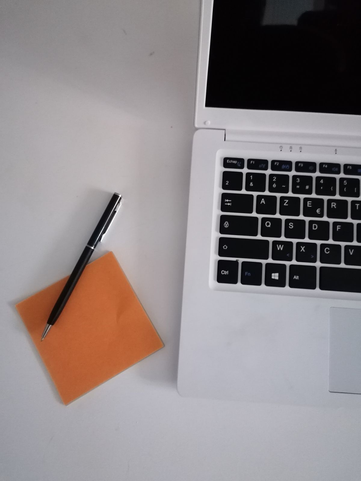 Carnet de notes et ordinateur pour préparer ses prompts immobiliers