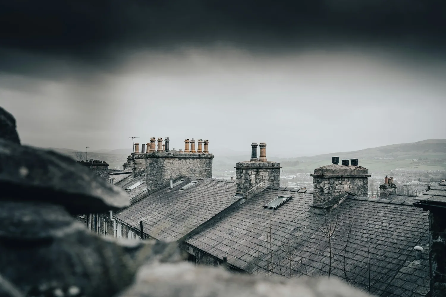 Ciel nuageux gris au-dessus d’une ligne de toitures et d’une cheminée