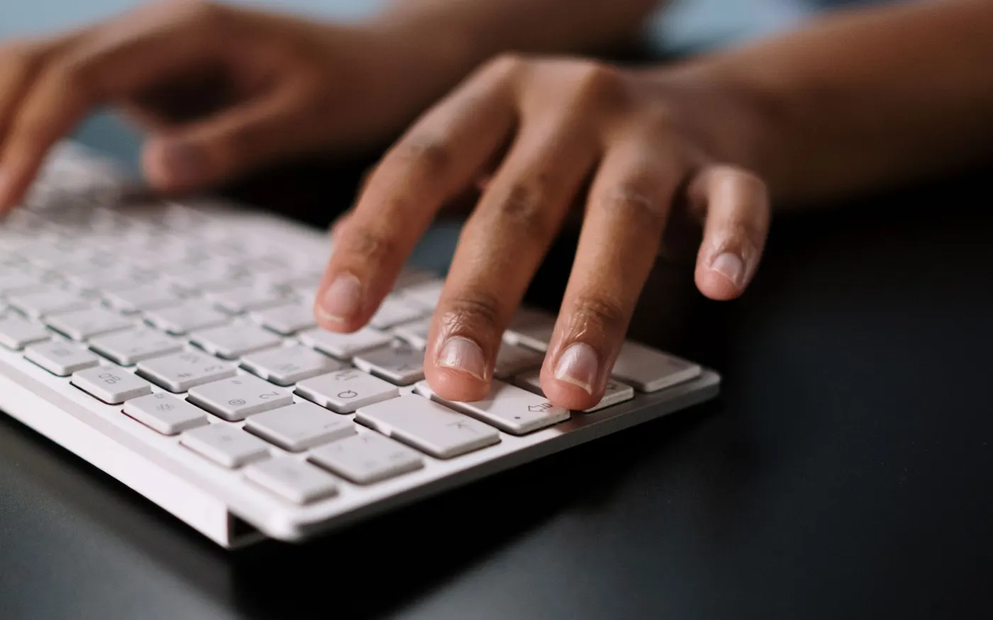Des mains tapent sur un clavier blanc