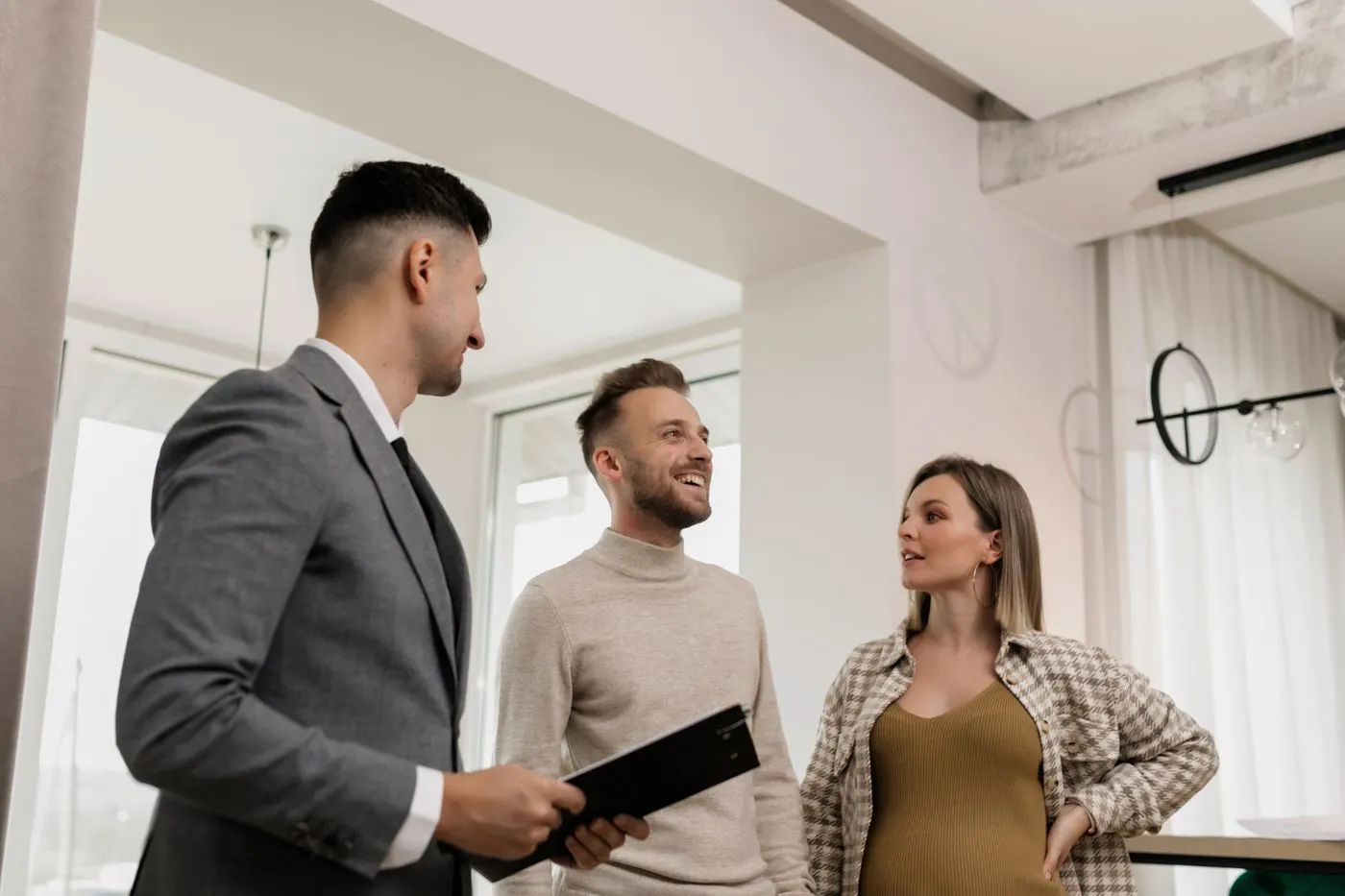 Un commercial en costume échange avec un couple, dans un séjour clair