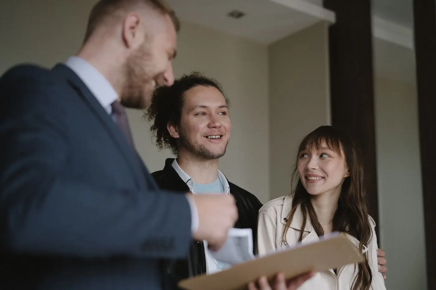 Un agent immobilier remet un document à un couple souriant