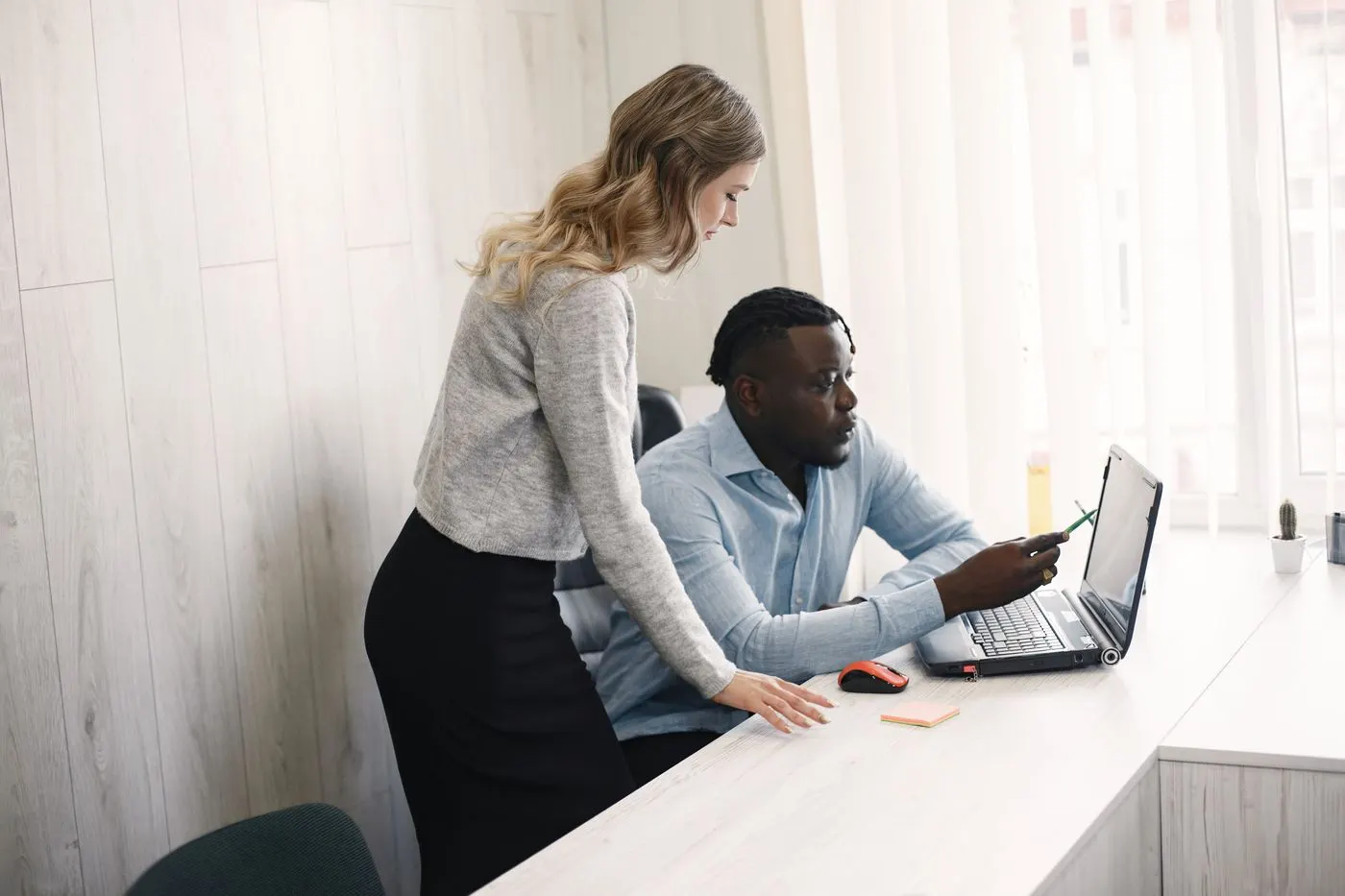 Deux collaborateurs d’agence regardent ensemble l’écran d’un ordinateur portable