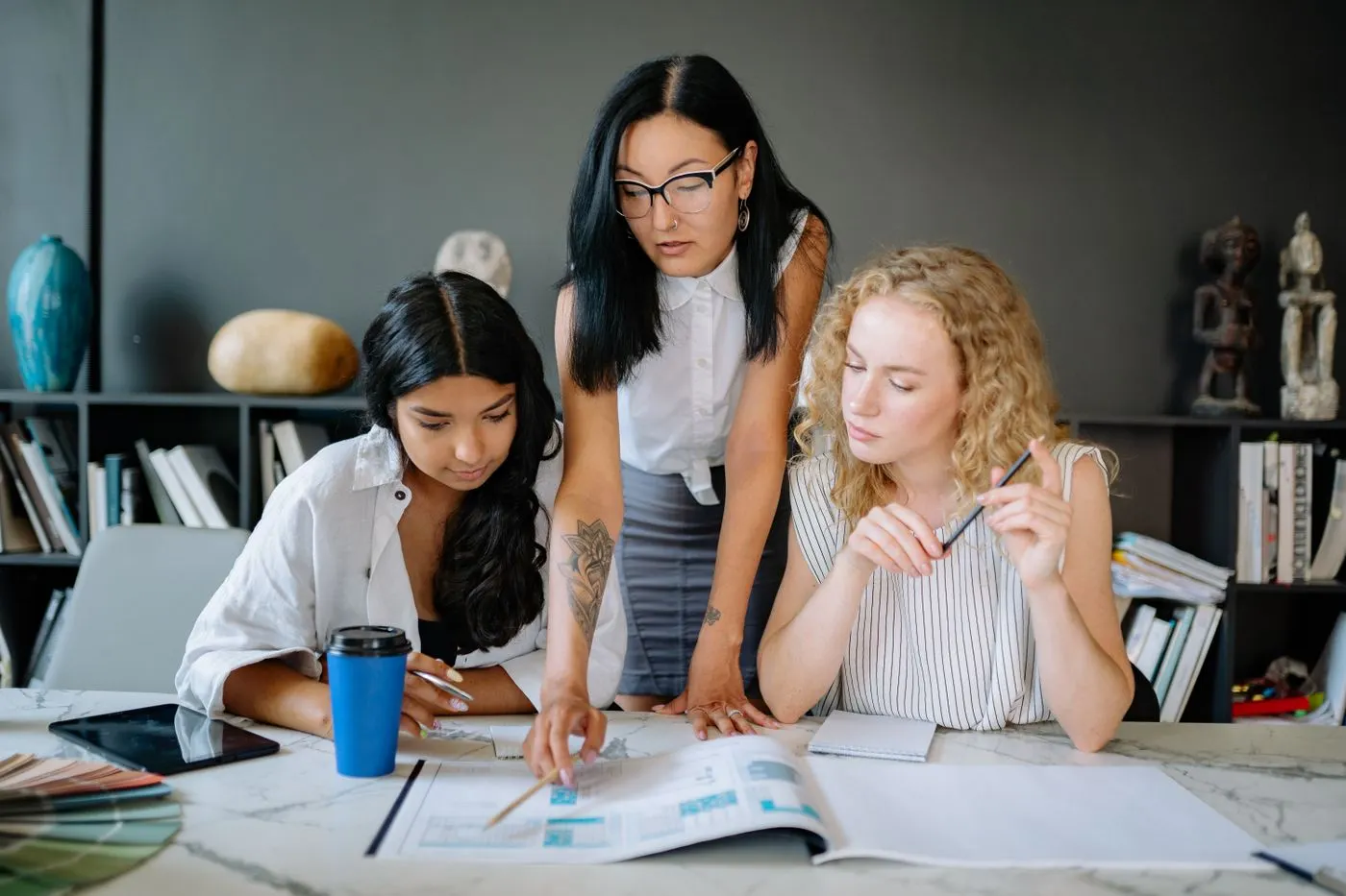 Trois collaboratrices penchées sur des documents, autour d’une table de travail