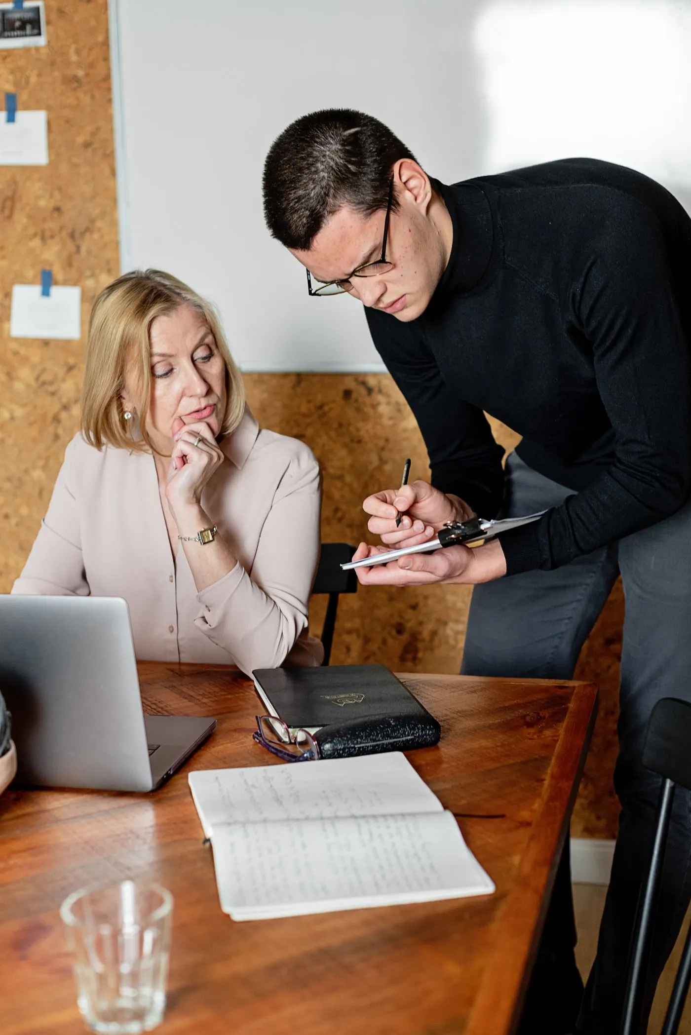 Une femme et un homme travaillent ensemble à une table, entre un ordinateur portable et des notes
