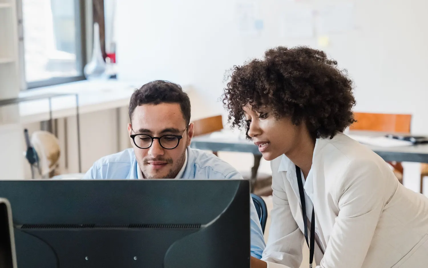 Deux collègues regardent ensemble l’écran d’un ordinateur de bureau