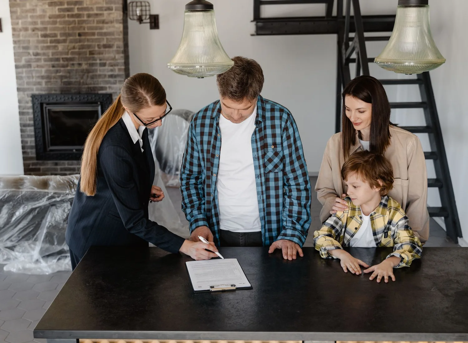 Une conseillère présente un document à signer, posé sur un porte-bloc, à un couple accompagné d’un enfant