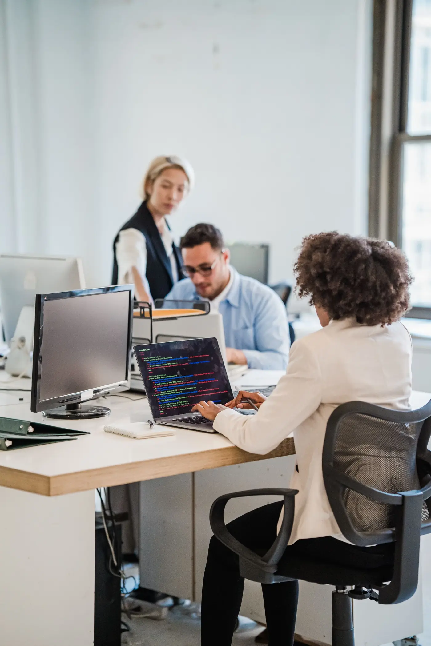 Trois personnes au travail dans un open space clair