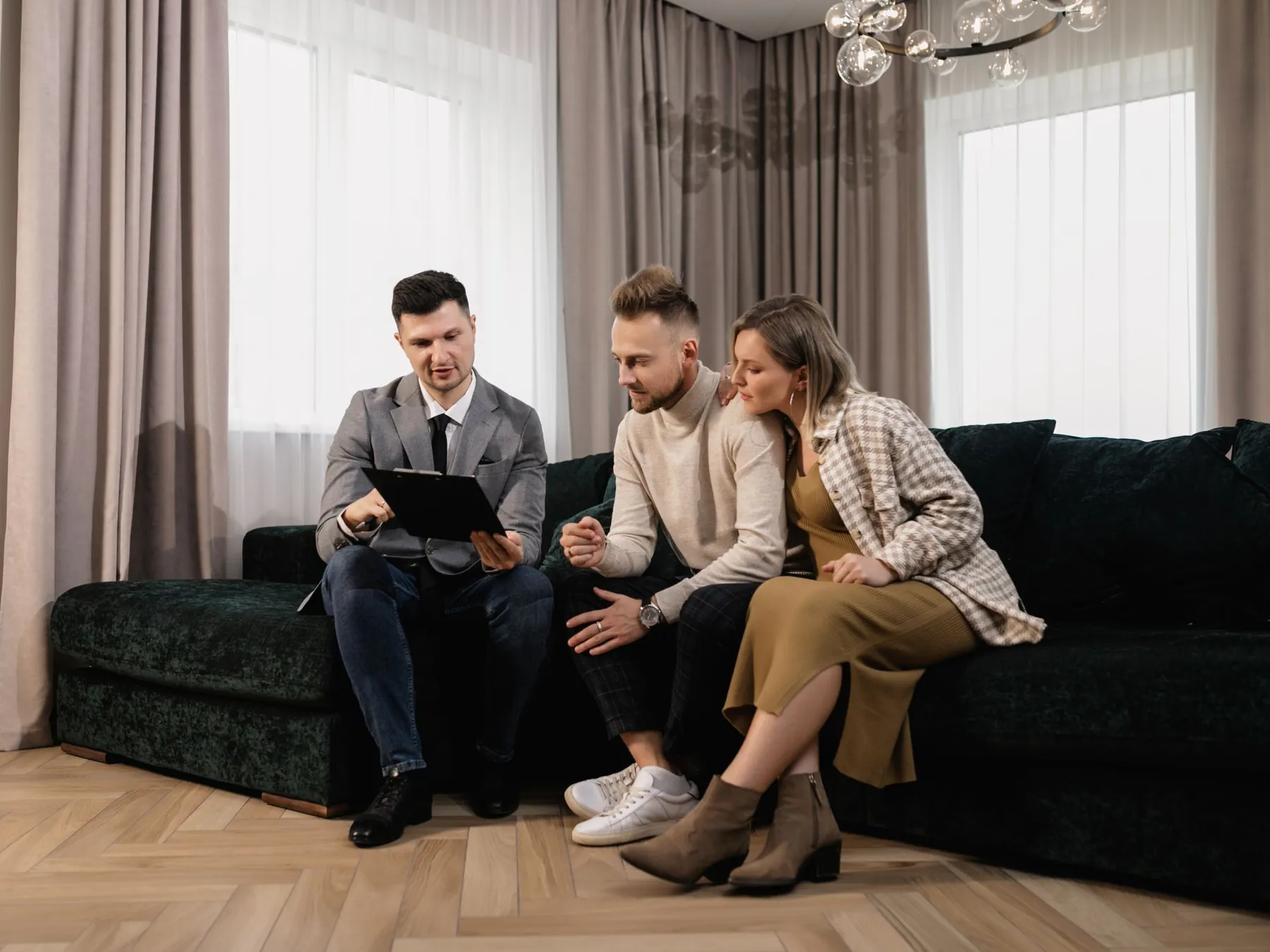 Un conseiller immobilier présente un dossier à un couple assis dans son salon