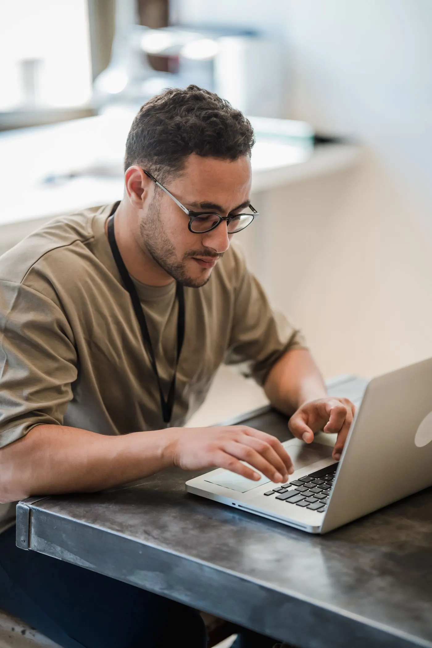 Un homme à lunettes travaille sur son ordinateur portable, à une table d’atelier