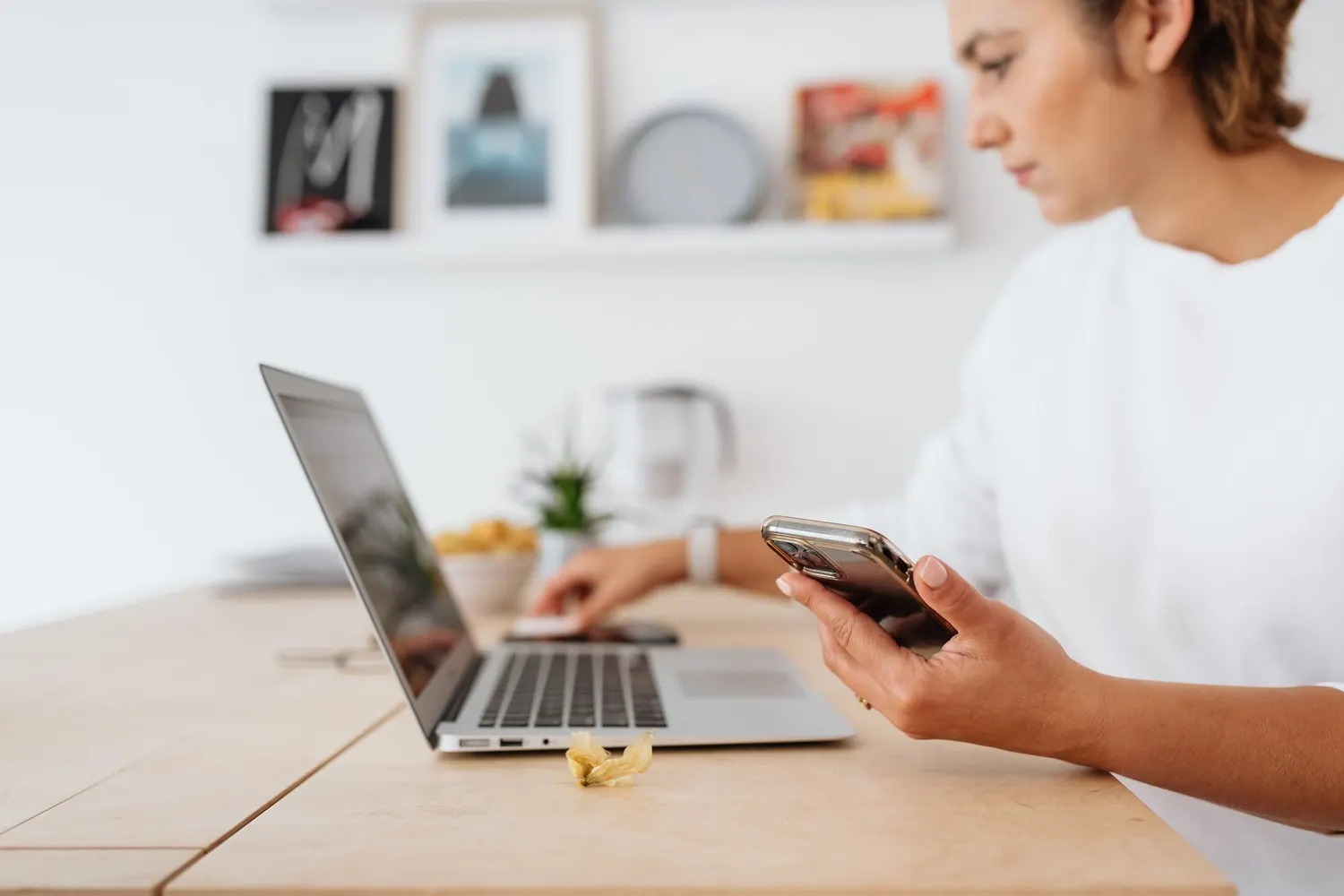 Une professionnelle consulte son téléphone à son bureau, devant un ordinateur portable ouvert