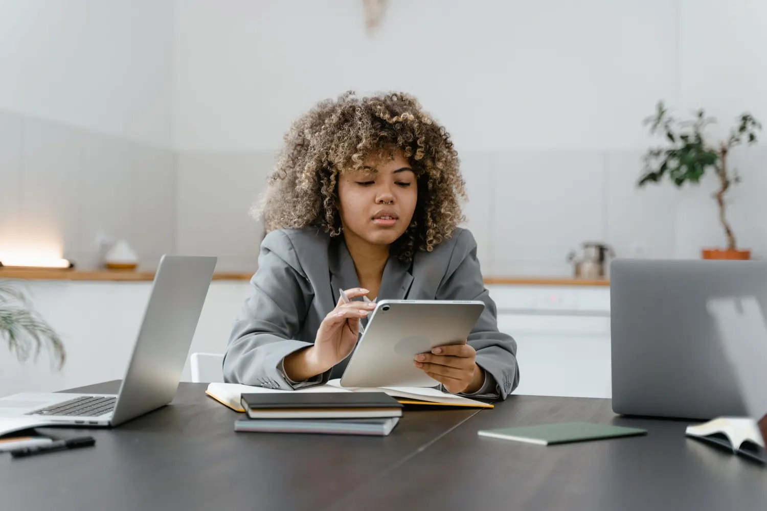 Une professionnelle consulte une tablette entre deux ordinateurs portables