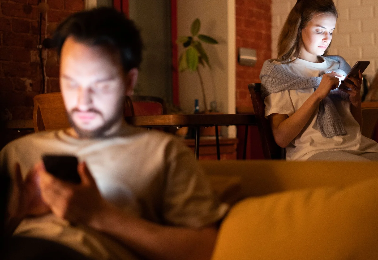 Un homme et une femme consultent leur téléphone le soir, chez eux