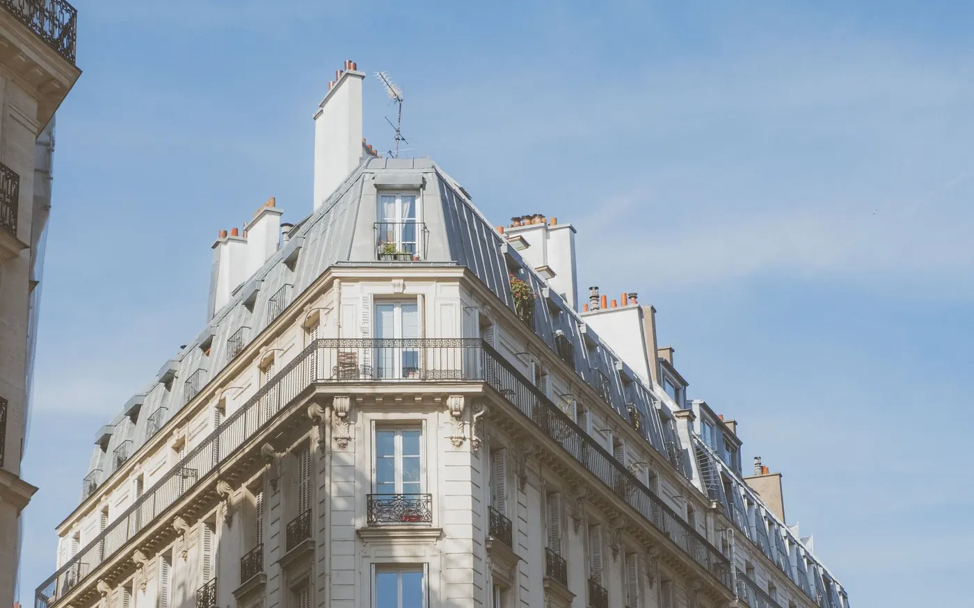 Un immeuble haussmannien à l’angle d’une rue, sous un ciel bleu
