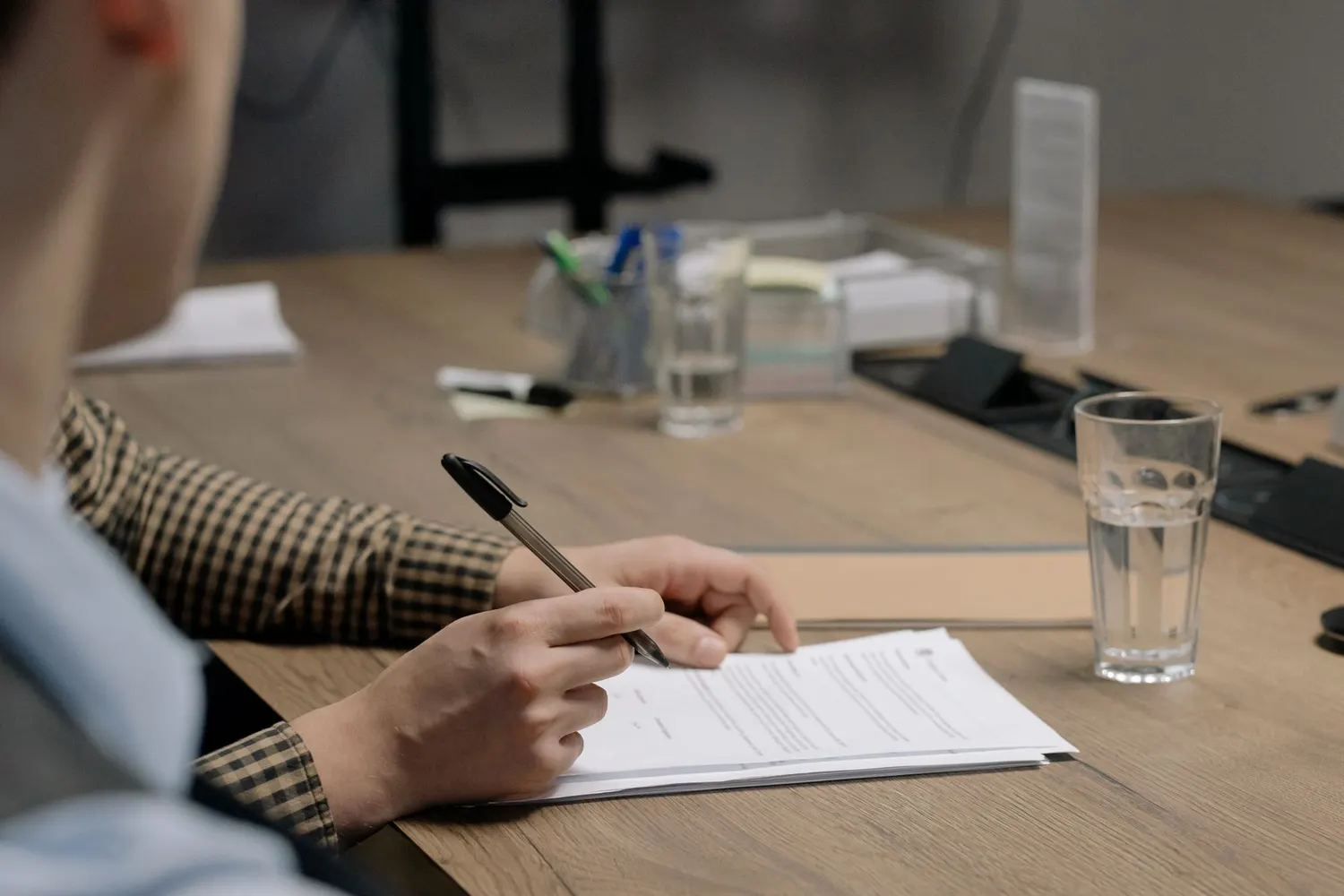 Une main tient un stylo au-dessus d’un contrat posé sur une table de réunion