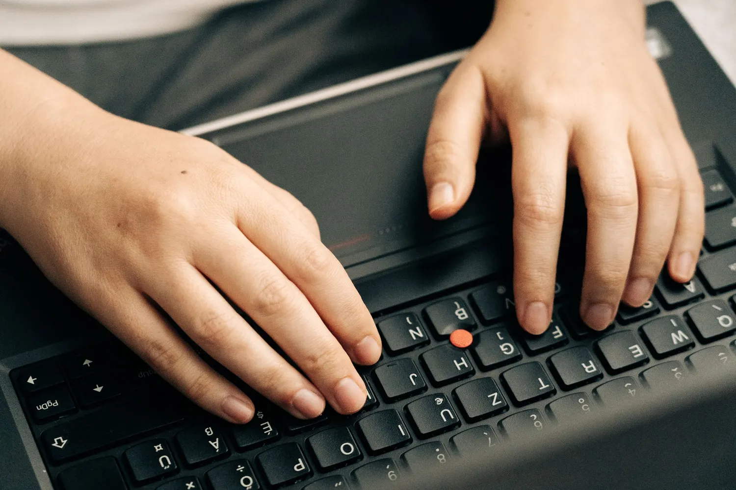 Deux mains posées sur le clavier d’un ordinateur portable